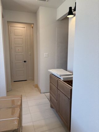 Model Home A stylish hallway with warm wood cabinetry and modern black light fixtures in Johnson Ranch by Perry Homes (Bulverde, TX).