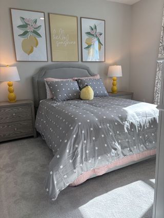 A cozy bedroom with gray polka dot bedding, yellow accents, and cheerful artwork, creating a bright and inviting atmosphere.