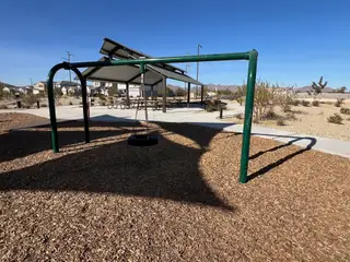A playground with a swing set and picnic area in Bentridge – Peak Series by Landsea Homes (Buckeye, AZ).