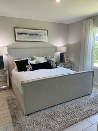 A cozy bedroom with a plush bed, elegant lamps, and soft lighting. Neutral tones create a serene atmosphere.