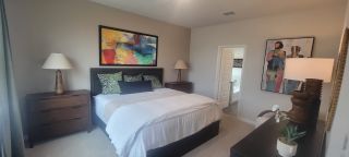 A cozy bedroom featuring a warm palette, abstract art, wooden dressers, and stylish lamps for a tranquil ambiance.