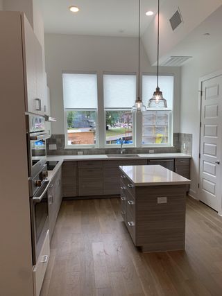 Model Home A modern kitchen with sleek cabinetry, an island, pendant lighting, and bright windows.