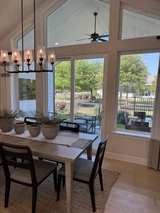 A bright dining area with modern chandelier, large windows, and a view of the garden, offering a cozy, elegant ambiance.