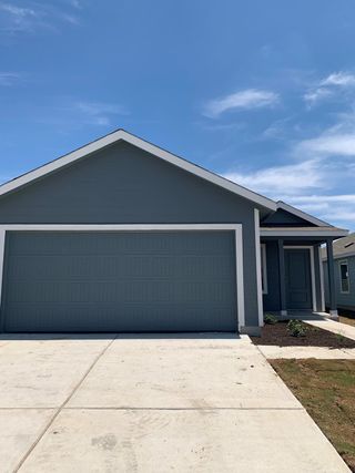 Street view A sleek gray home with a modern design and fresh landscaping in Rancho Del Cielo by Lennar (Jarrell, TX).