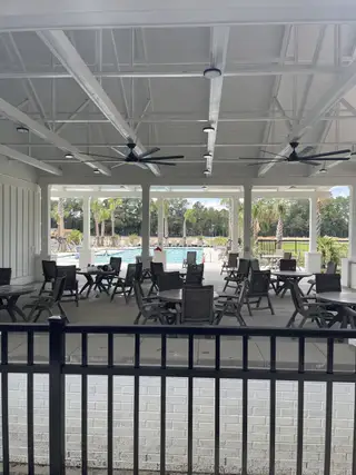 Community Amenities A spacious outdoor area with modern seating, ceiling fans, and a pool view in Six Oaks by Mungo Homes (Summerville, SC), perfect for relaxation and gatherings.