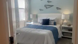 A cozy bedroom with a soft blue accent wall, geometric decor, and modern lamps, exuding a peaceful ambiance.