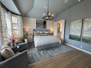 Elegant bedroom with a plush bed, chic chandelier, and serene decor in soft blues and grays.