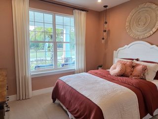 A cozy bedroom with warm tones, plush pillows, and a large window offering serene outdoor views.