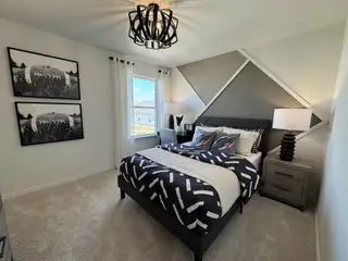 Model Home A modern bedroom featuring geometric wall art, chic bedding, and unique lighting, creating a stylish and inviting space.