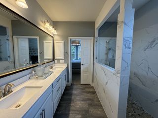Model Home A spa-like bathroom with a glass-enclosed shower, dual vanity, and marble-style tile in Sendero at Veramendi by Pulte Homes (New Braunfels, TX).