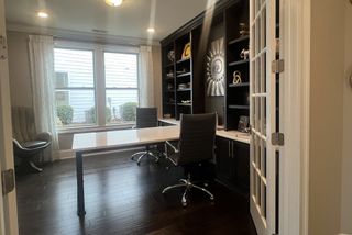 Model Home Sophisticated home office featuring sleek desks, modern chairs, and built-in shelving under soft lighting.