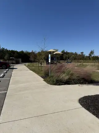 A serene park with a playground and landscaped greenery in Horizon Lake by Pulte Homes (Leander, TX).