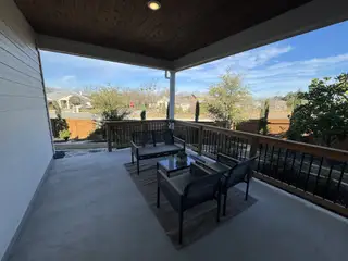 An inviting outdoor living space with a wooden ceiling, stylish outdoor furniture, and a railing that offers a relaxing atmosphere for enjoying the Texas breeze.