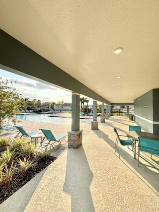 A covered outdoor seating area with vibrant blue chairs overlooking the community pool in Concorde by D.R. Horton (Sanford, FL).