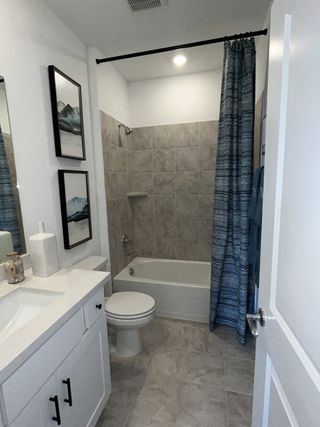 A modern bathroom featuring a tiled tub, sleek white vanity, and decorative wall art for a stylish touch.