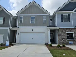 A modern townhouse with gray siding and brick accents in The Enclave at Whitewater Creek by Direct Residential Communities (Union City, GA).