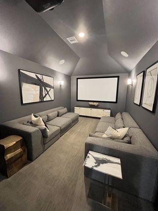 Model Home A modern home theater featuring plush gray sofas, abstract artwork, and a large screen for ultimate entertainment.