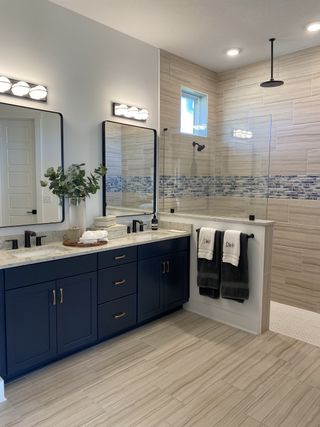 Model Home A stylish bathroom with navy cabinetry, dual sinks, a large glass shower, and sleek black fixtures for a modern touch.