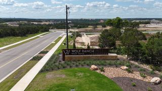 Scenic entrance to Park Collection At Wolf Ranch by Tri Pointe Homes, showcasing lush greenery. (Georgetown, TX)