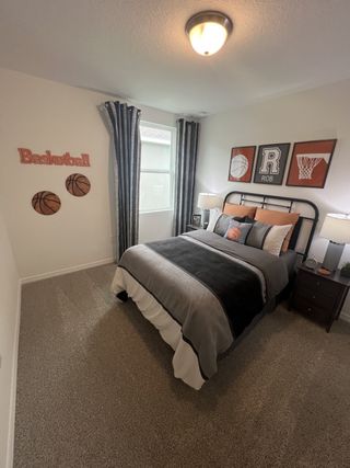 A cozy bedroom with basketball-themed decor, soft carpeting, and a neatly made bed.