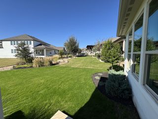 Model Home A serene backyard with manicured landscaping, open green space, and charming homes in the background.