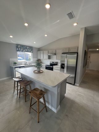 A modern kitchen with a spacious island, sleek appliances, gray cabinetry, and stylish barstools.