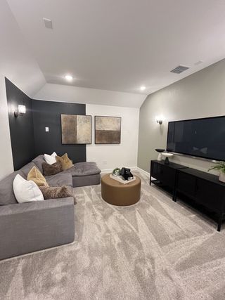 Model Home A cozy media room with a plush gray sectional, abstract art, and modern lighting.
