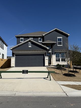 A modern dark-toned home with stone accents in Lakeside at Tessera on Lake Travis by Saratoga Homes (Lago Vista, TX).