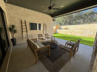 Model Home A covered outdoor patio with a ceiling fan, built-in TV, and a peaceful backyard view—ideal for relaxing or entertaining.