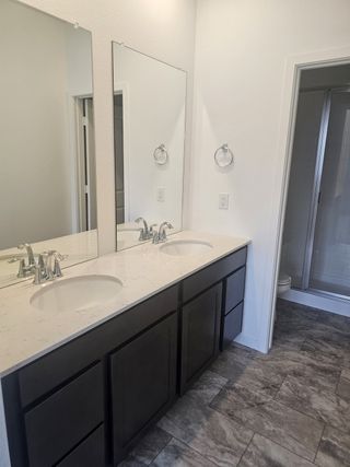 A modern bathroom featuring a sleek double vanity, large mirrors, and elegant gray tile flooring.