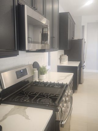Model Home A sleek kitchen features dark cabinetry, stainless steel appliances, and elegant marble countertops.