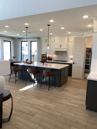 A modern kitchen with sleek cabinetry, pendant lights, and a large island featuring bar seating and stylish decor.