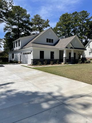 A modern white home with a spacious driveway and lush greenery in Summerville Single Family Homes by Ryan Homes (Summerville, SC).
