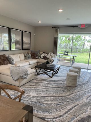 A cozy living room featuring a large sectional sofa, modern coffee table, and wide windows overlooking a lush garden.