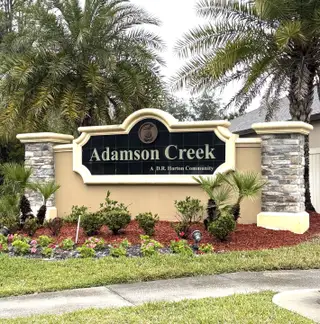 Welcome to Adamson Creek by D.R. Horton in Cocoa, FL, featuring a beautifully landscaped community entrance with palm trees.
