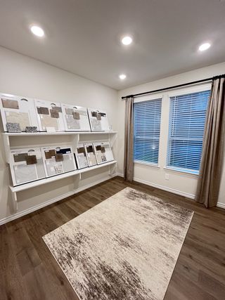 Model Home A cozy design room with sample boards, accent rug, and large window with drapes, creating an inviting workspace.