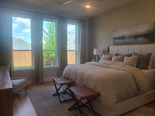 A serene bedroom featuring large windows, a plush bed, and soft lighting for a relaxing ambiance.