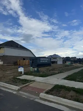 Street view New homes under construction with spacious lots in Sunfield by Brightland Homes (Buda, TX).