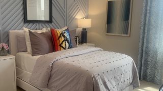 A cozy bedroom with textured walls, modern art, and vibrant pillows creating a chic, inviting atmosphere.