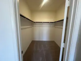 Spacious walk-in closet with carpet flooring, ample hanging space, and bright lighting.