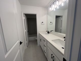 A sleek bathroom with dual sinks, black fixtures, and bright lighting, offering a modern and functional design.