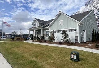 Street view A charming gray home with a porch and manicured lawn in Harmony by Eastwood Homes (Harrisburg, NC).
