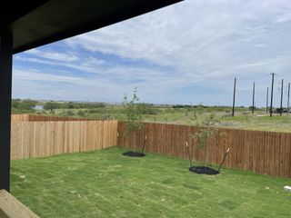 Model Home A serene backyard with a wooden fence and young trees in Royal Crest by Meritage Homes (San Antonio, TX).