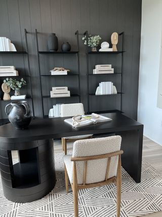 A modern home office with dark paneled walls, sleek shelving, and a minimalist desk creates a sophisticated workspace.