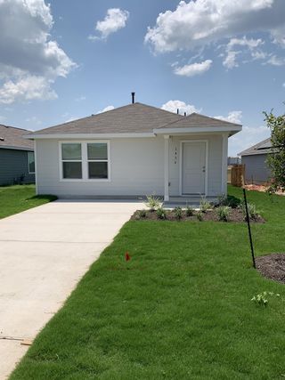 A cozy single-story home with a lush green lawn, white exterior, and welcoming entryway in Sunset Oaks by Lennar.