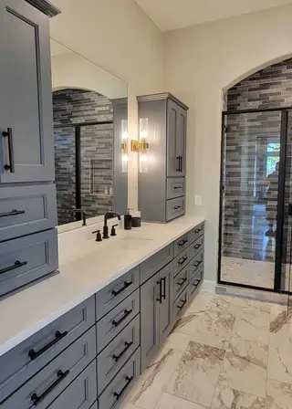 A chic bathroom with elegant gray cabinetry, sleek lighting, and a stylish glass shower.