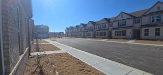 A row of newly constructed townhomes with brick facades and well-paved walkways in a quiet neighborhood in Bethlehem, GA.