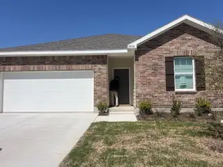A charming brick home with a white garage and landscaped lawn in Ranch at Duck Creek by Starlight Homes (Fort Worth, TX).