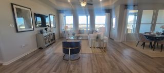 Model Home A spacious living area with sleek flooring, modern decor, large windows, and an elegant dining nook.