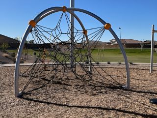 Community Amenities A modern playground with a rope climbing structure in The Lakes at Rancho El Dorado by Brightland Homes (Maricopa, AZ).
